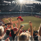 A crowd of enthusiastic fans cheering and waving red towels at a baseball game