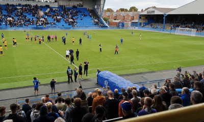 Post-match scene at Brunton Park showing Carlisle players, staff and supporters on the pitch and in the stands after a heavy defeat