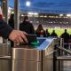A supporter scanning a smartphone at a football stadium turnstile