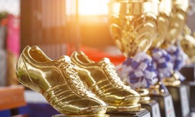 Golden football boot trophies lined up beside cups
