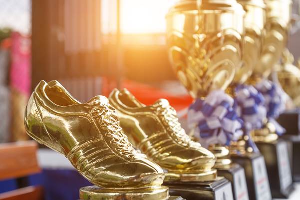 Golden football boot trophies lined up beside cups